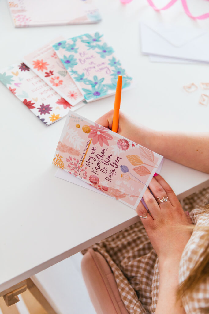 Louise from Two For Joy Illustration, writing in one of her card designs