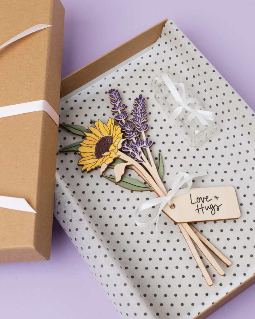 A DaphneRosa wooden flower gift set with bottle, gift box, and ribbon.