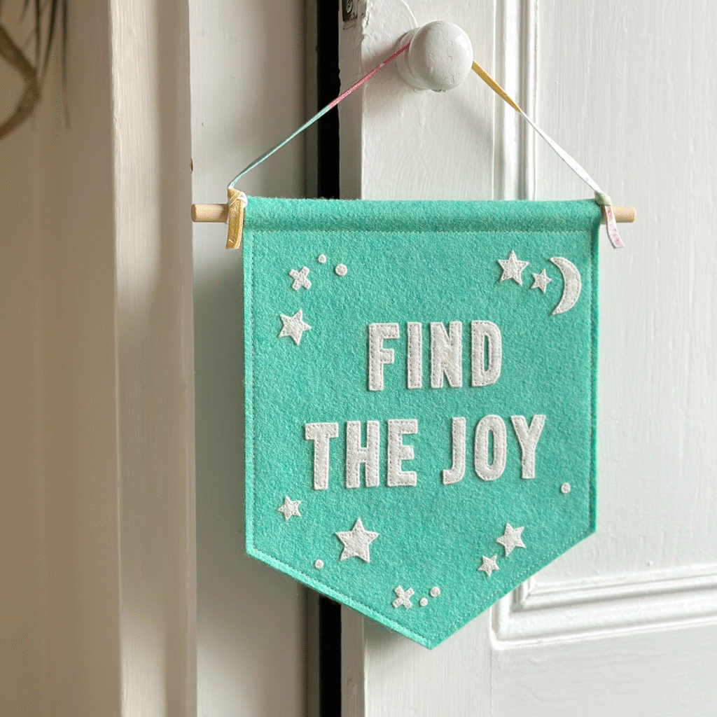 'Find The Joy' felt banner by Clara and Macy, hanging on a door