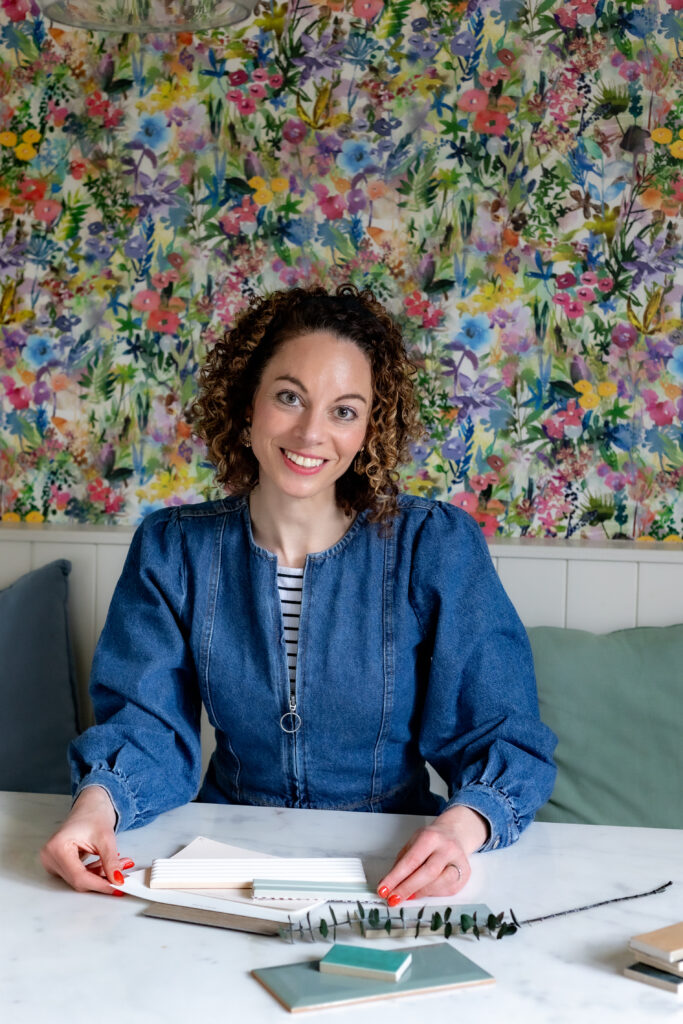 Becks from The Interior Lens sitting at a table, with interior design samples in front of her