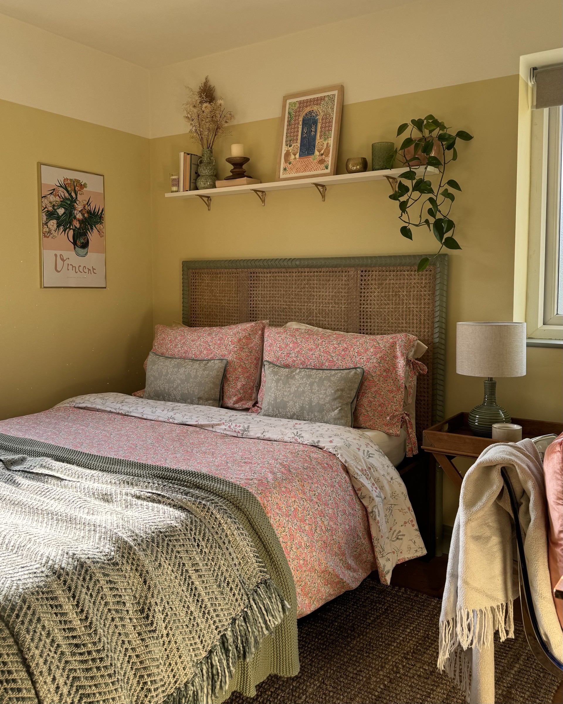 A bedroom designed by Becks from The Interior Lens, with soft muted yellow walls and touches of warm colour from bedding to artwork