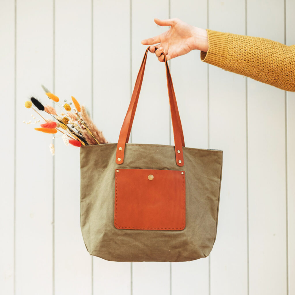 Tote bag by Rosanna Clare with dried flowers inside, being held by a hand