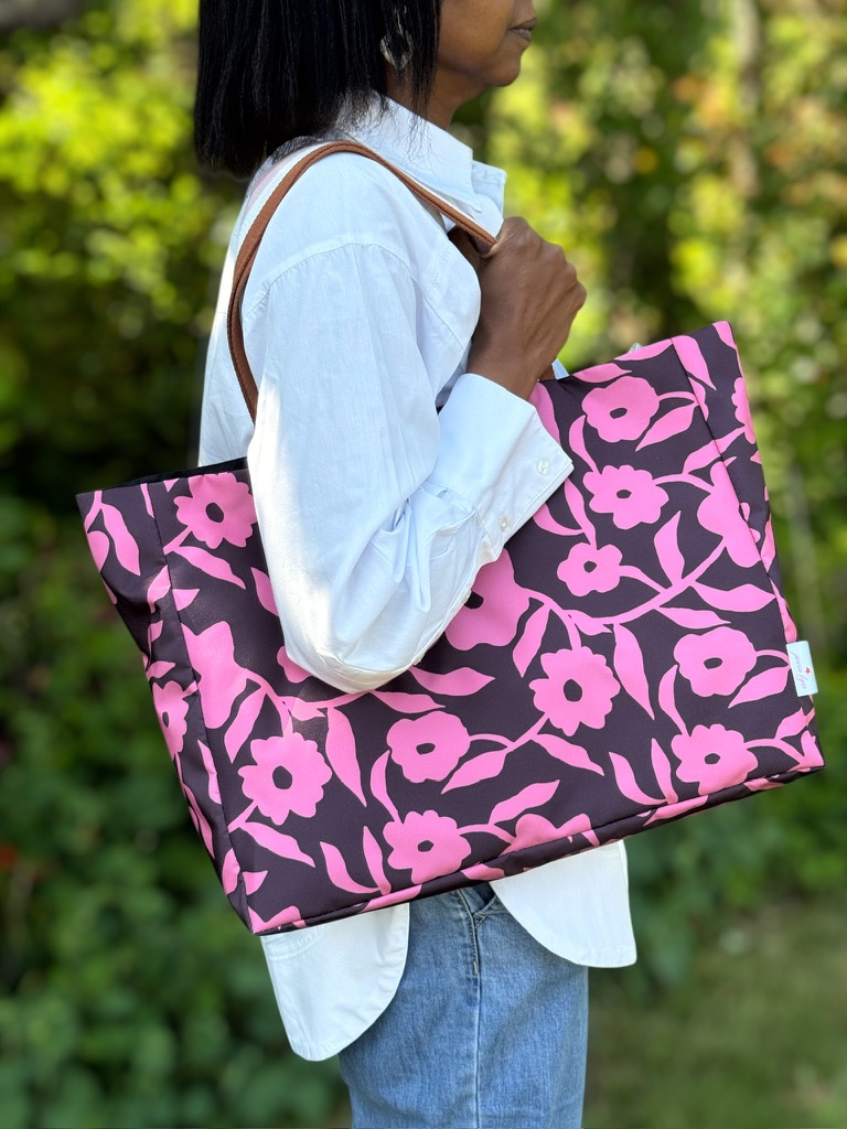 Patterned tote bag by Jennie Fynn, being held by Jenny in a leafy outdoor setting