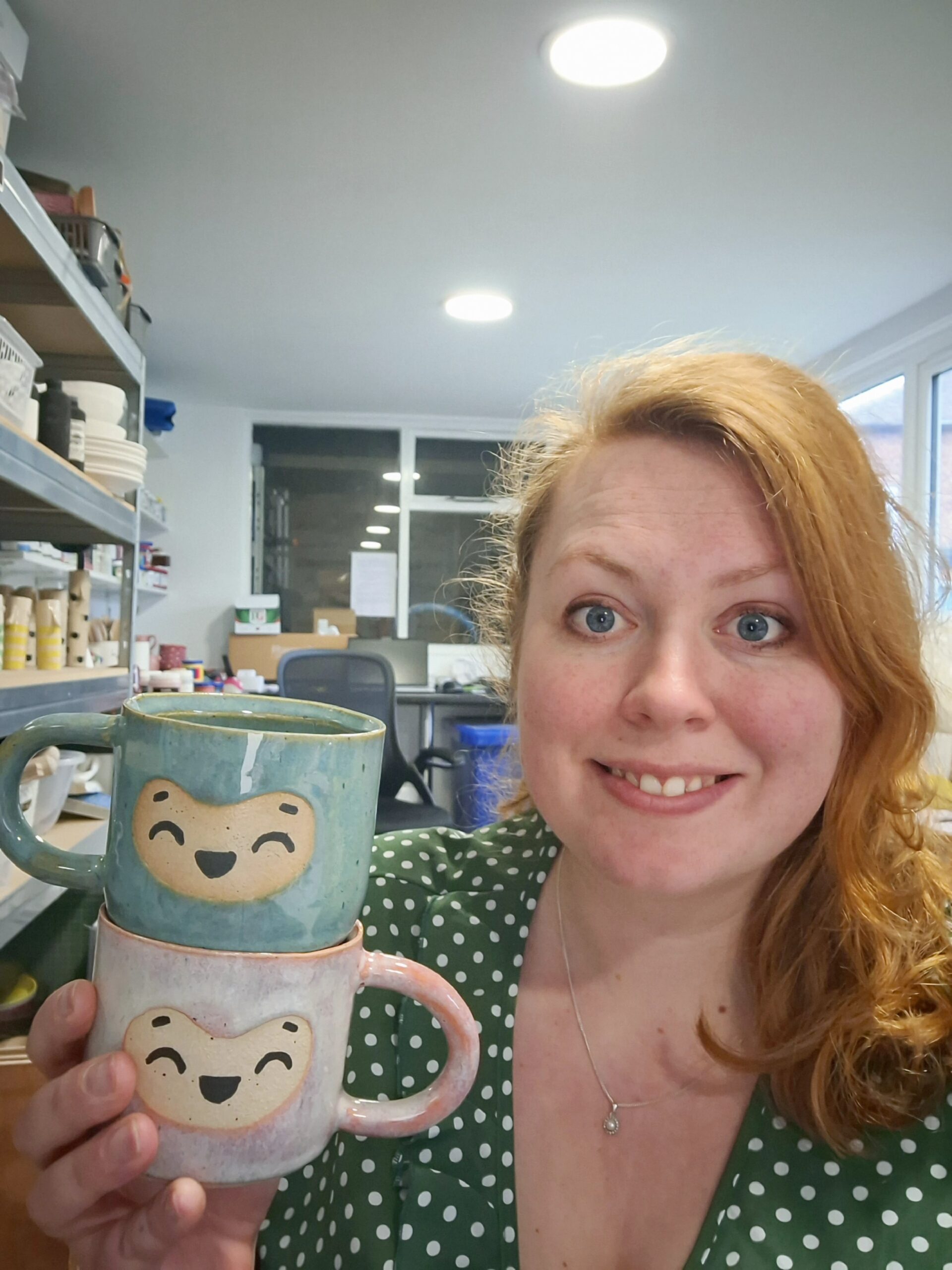 Emily from Millie's Ceramics, holding two of her smiley face mugs