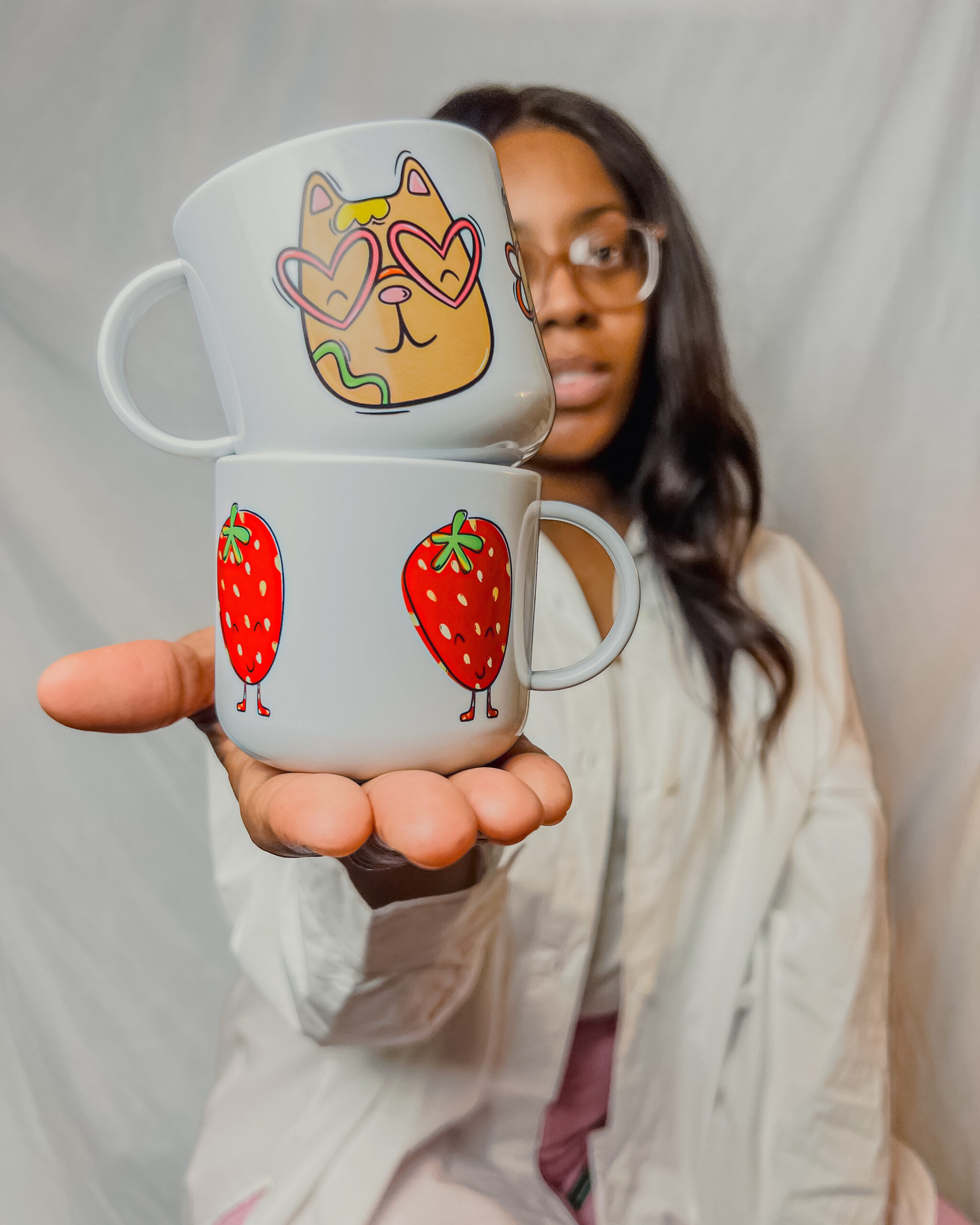 Natasha from Tish Tash Designs holding a couple of her illustrated children's mugs