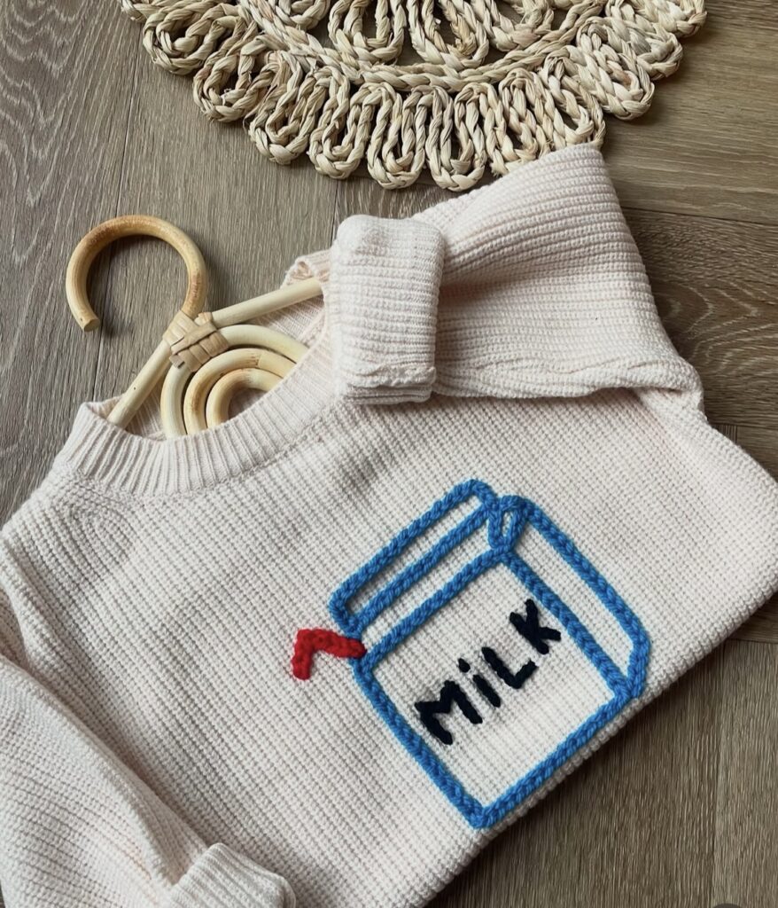 A kids jumper embroidered with a milk carton design created By Jay
