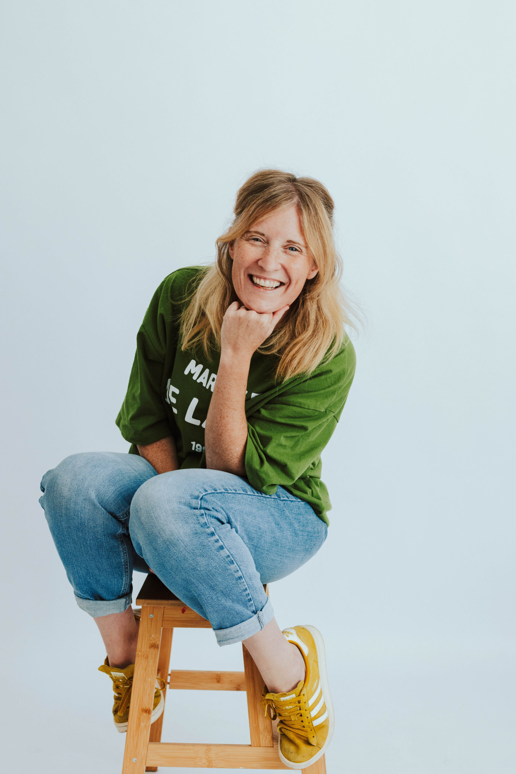 Sarah Burton Yorkshire based family and branding photographer, sat on a stool, laughing