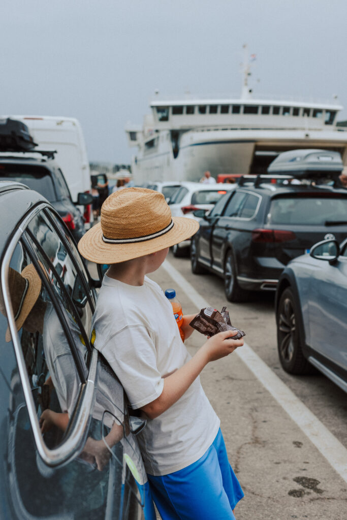 A photo by York family and brand photographer, Sarah Burton Photography, of a boy waiting by his family car to board a ferry