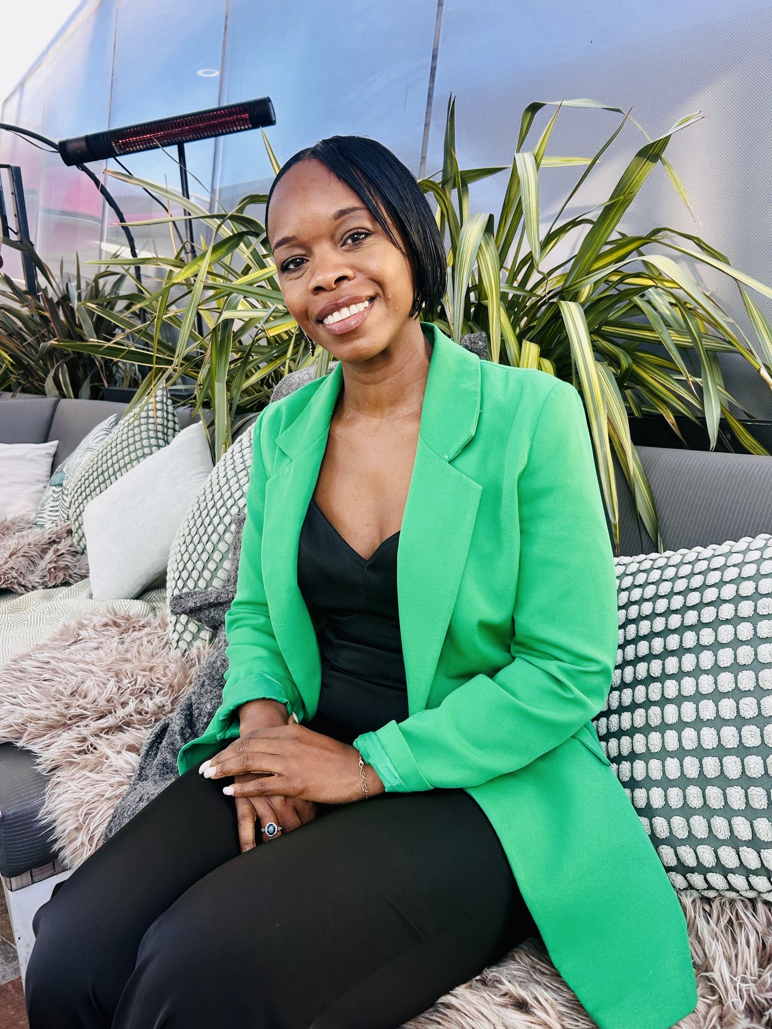 Artist Elaine Buchanan sat on an outside sofa, with a bright green jacket on