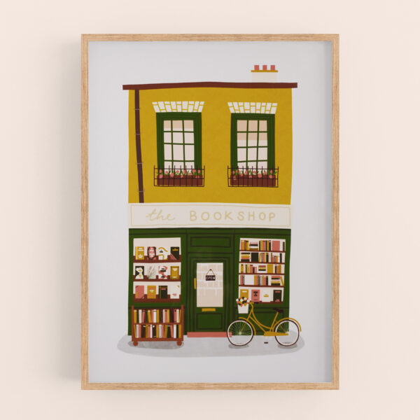 Bookshop illustration art print by Emily Nelson - with mustard yellow, dark green, and warm earthy colour palette. Shown in a light wood frame mockup, with a warm cream wall behind.