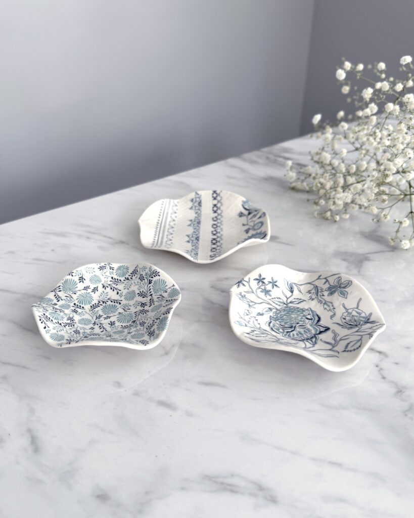Ceramic dishes with intricate surface pattern, by Alex Allday, placed on a marble worktop with some gyp in the background