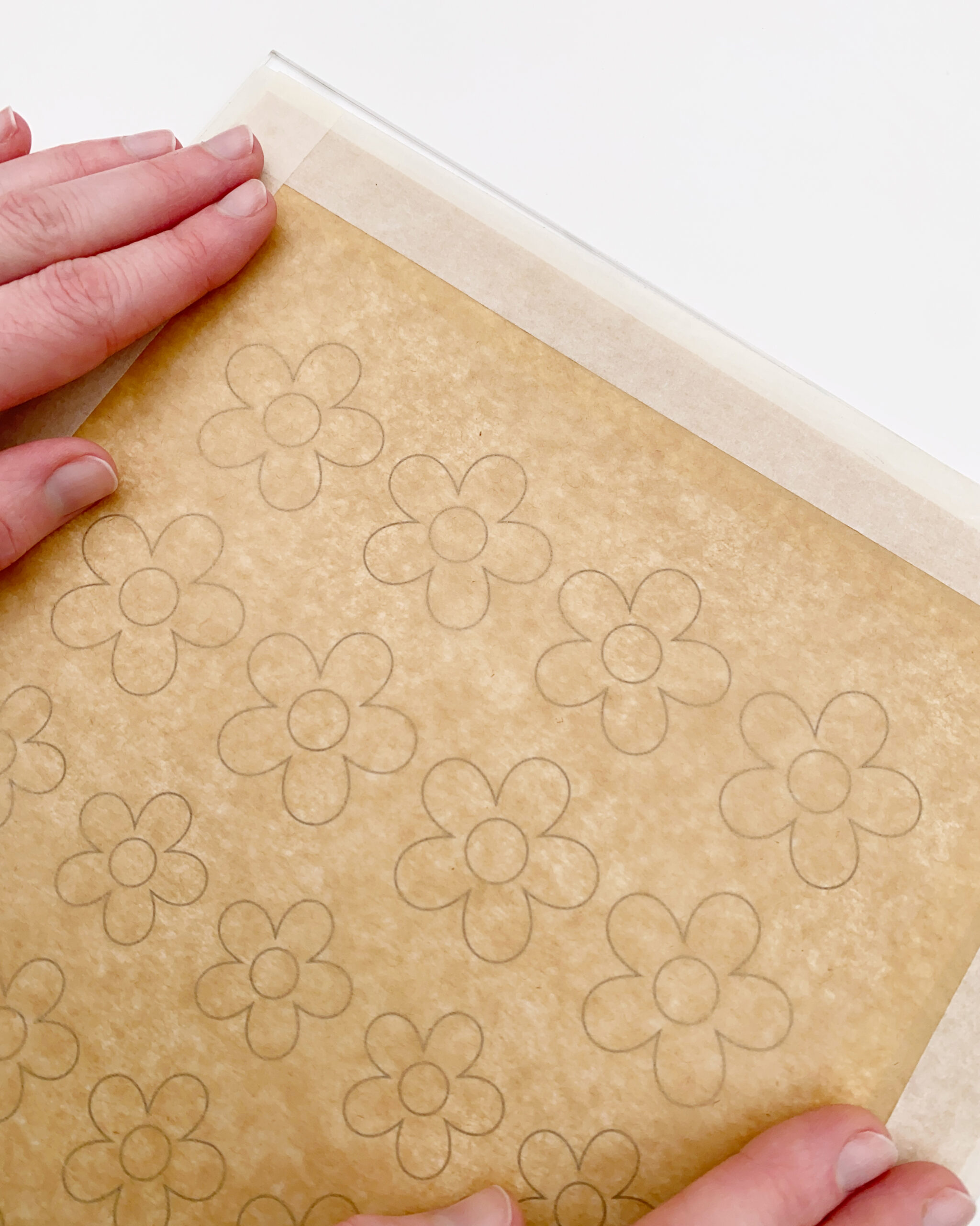 Piped chocolate flower decoration template taped onto a flat surface