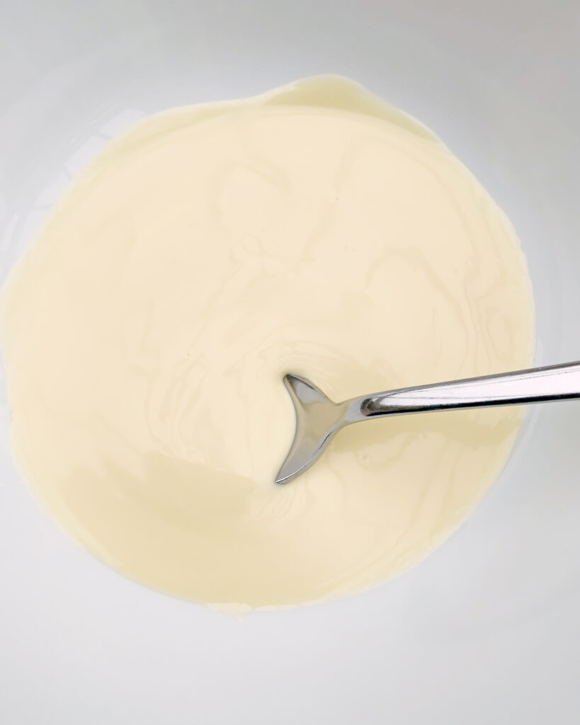 melted white chocolate in a bowl with a teaspoon