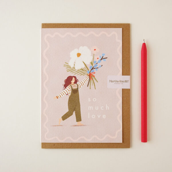 'So much love' illustrated card by Martha Ratcliff Illustration, with an illustration of a woman in dungarees holding a giant bunch of flowers on the front. A red pen is next to the card. The envelope is brown kraft.