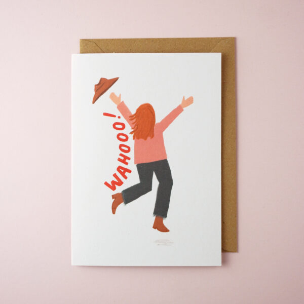 "Wahooo!" celebration card by Jade Fisher, with an illustration of a woman running or skipping and throwing her hat in the air on the front. The envelope is brown kraft.