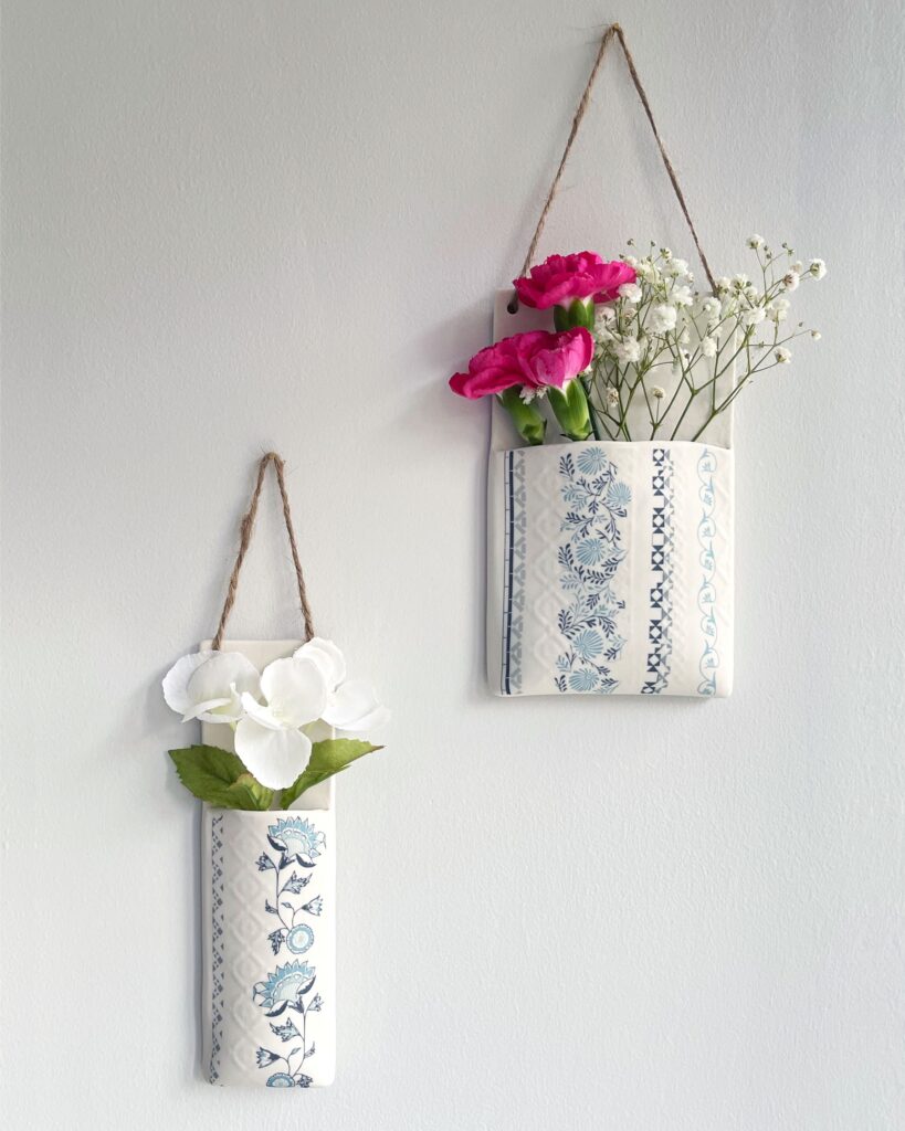 Wall-hanging planter pockets by Alex Allday Ceramic and Surface Pattern Designer, hanging on the wall with flowers inside
