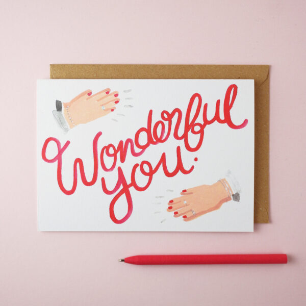 "Wonderful you" card by Jade Fisher, with an illustration of a woman's hands clapping and red handwritten style text on the front. A red pen is next to the card. The envelope is brown kraft.