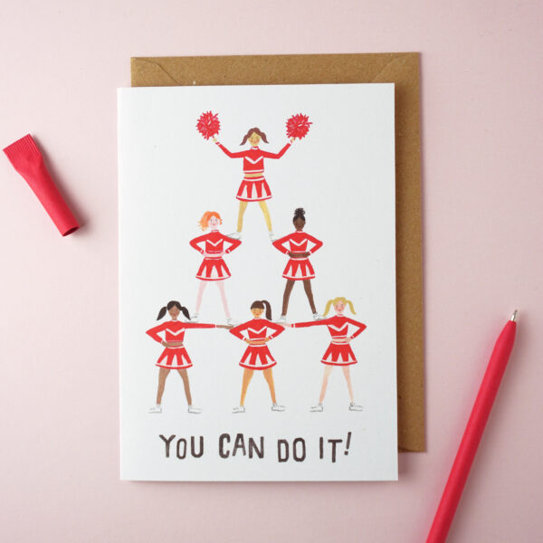 "You can do it" card by Jade Fisher, with an illustration of women cheerleaders creating a pyramid on the front. A red pen is next to the card. The envelope is brown kraft.